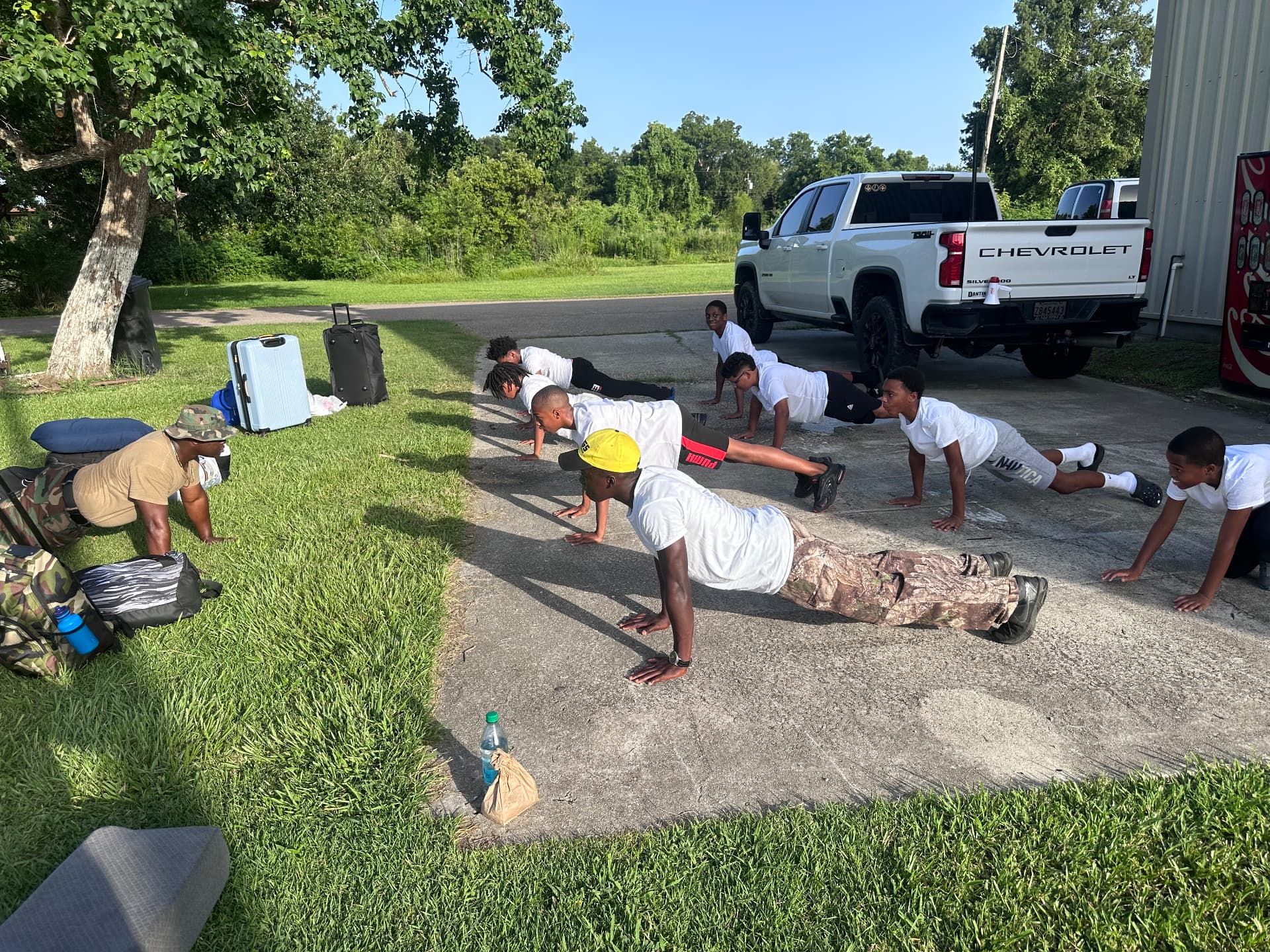 Mentors and young men doing push-ups together outdoors during morning fitness